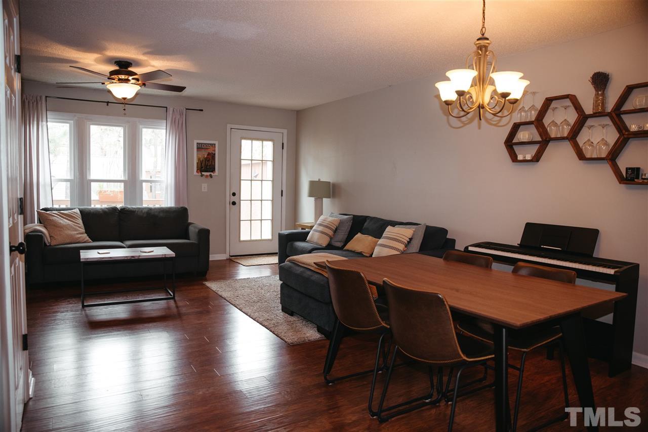 7020 Epping Forest Drive Raleigh, NC 27613 - Photo 4 of 29 a living room with furniture a chandelier and a flat screen tv