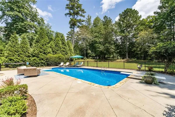 a view of a swimming pool with a lounge chair and trees in the background