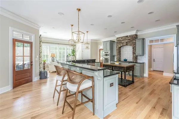 a kitchen with stainless steel appliances kitchen island granite countertop a stove a refrigerator and a dining table with wooden floor