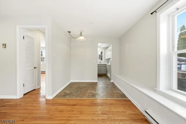 a view of a hallway with wooden floor and a bathroom