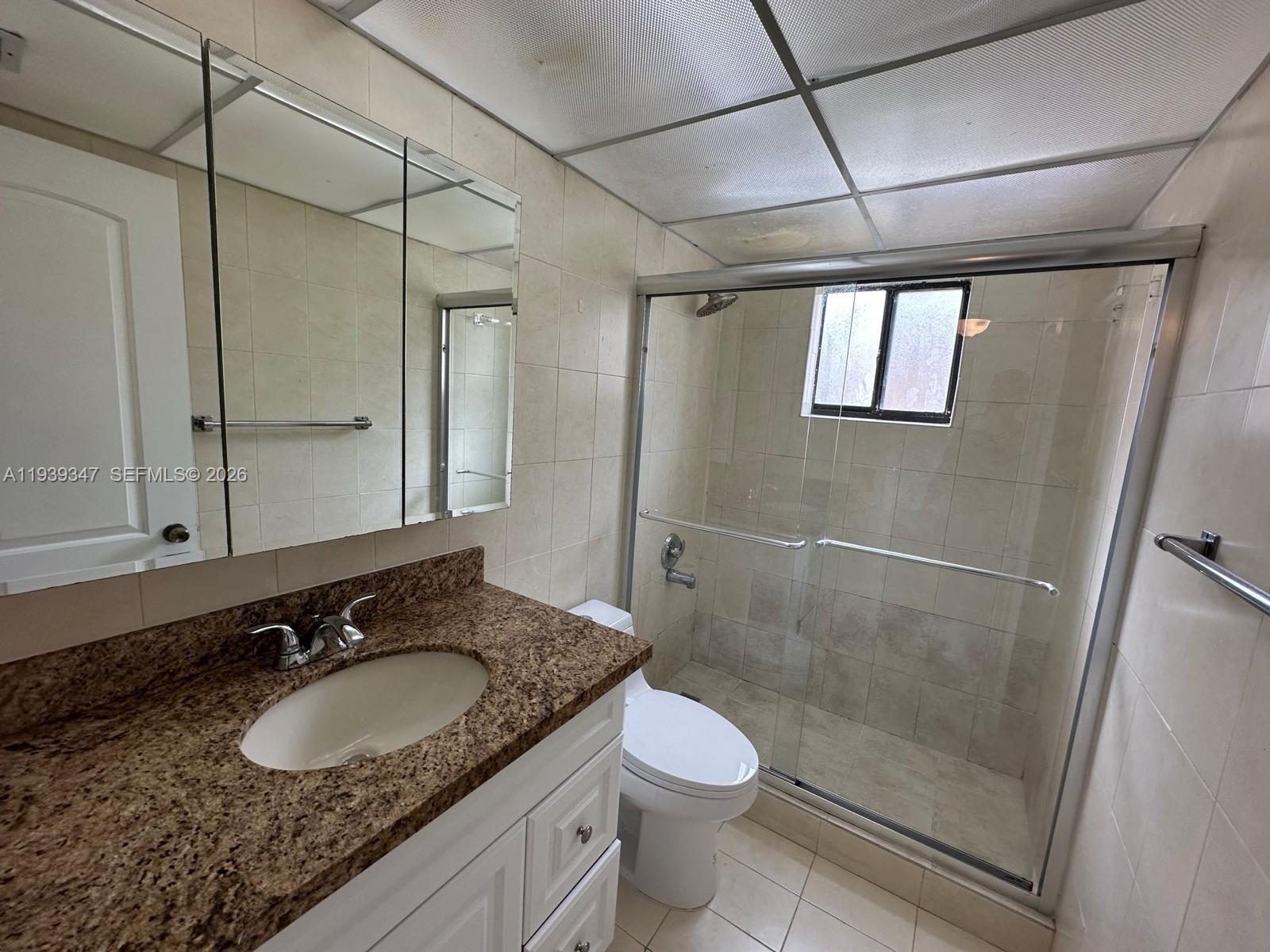 8540 Southwest 133rd Avenue Road, Unit 312 Miami, FL 33183 - Photo 10 of 15 a bathroom with a granite countertop sink a mirror and a shower