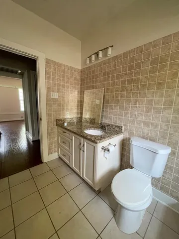 a bathroom with a granite countertop toilet a sink a mirror and shower