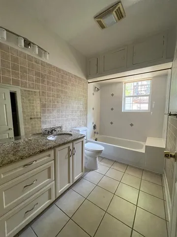 a bathroom with a granite countertop sink a toilet and bathtub