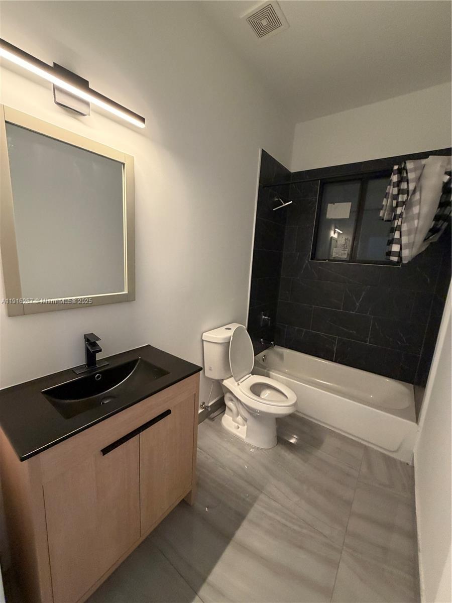 932 Southwest 10th Street, Unit 3 Hallandale Beach, FL 33009 - Photo 12 of 22 a bathroom with a granite countertop sink a toilet and a mirror