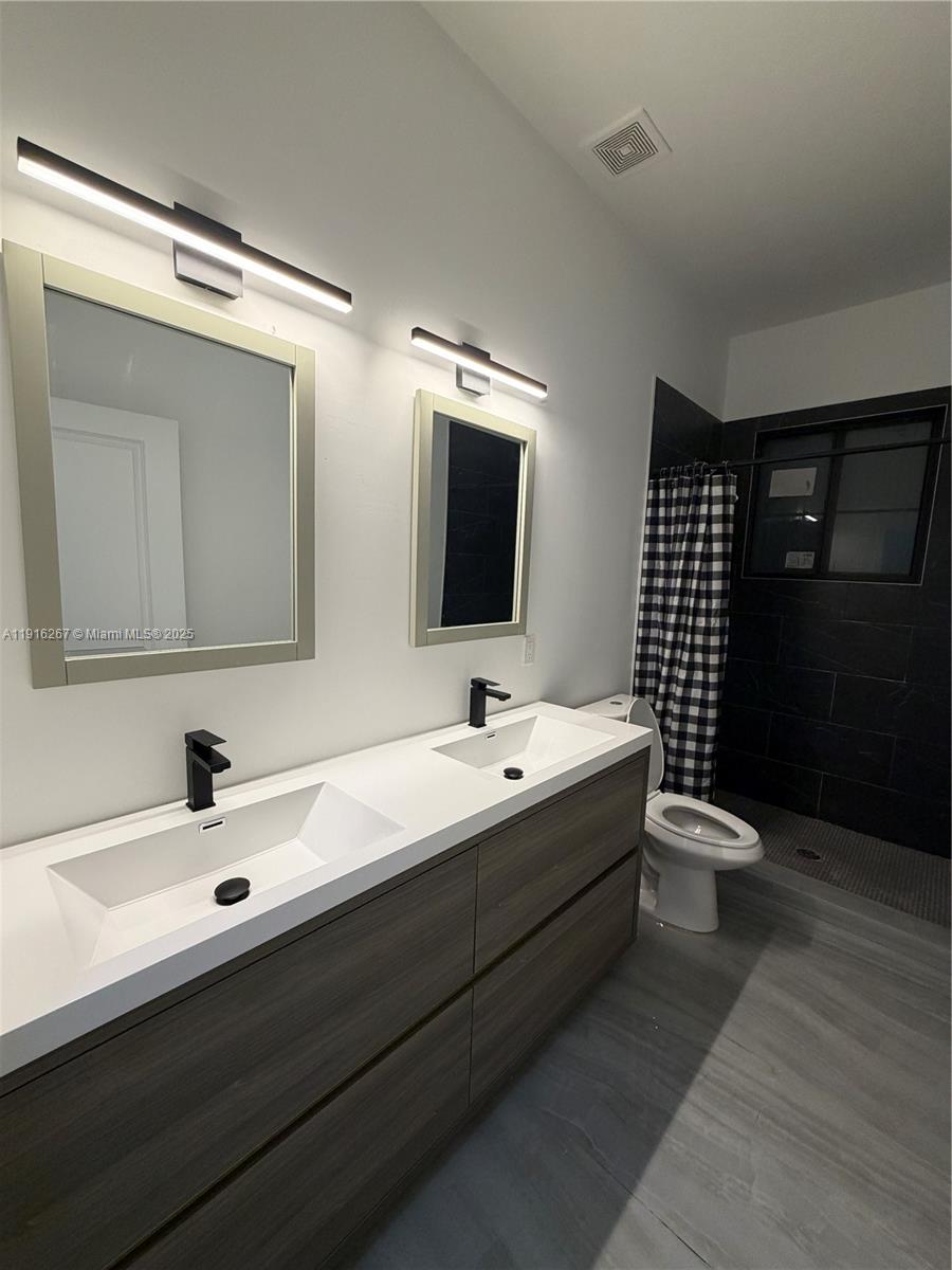 932 Southwest 10th Street, Unit 3 Hallandale Beach, FL 33009 - Photo 16 of 22 a bathroom with a double vanity sink and mirror