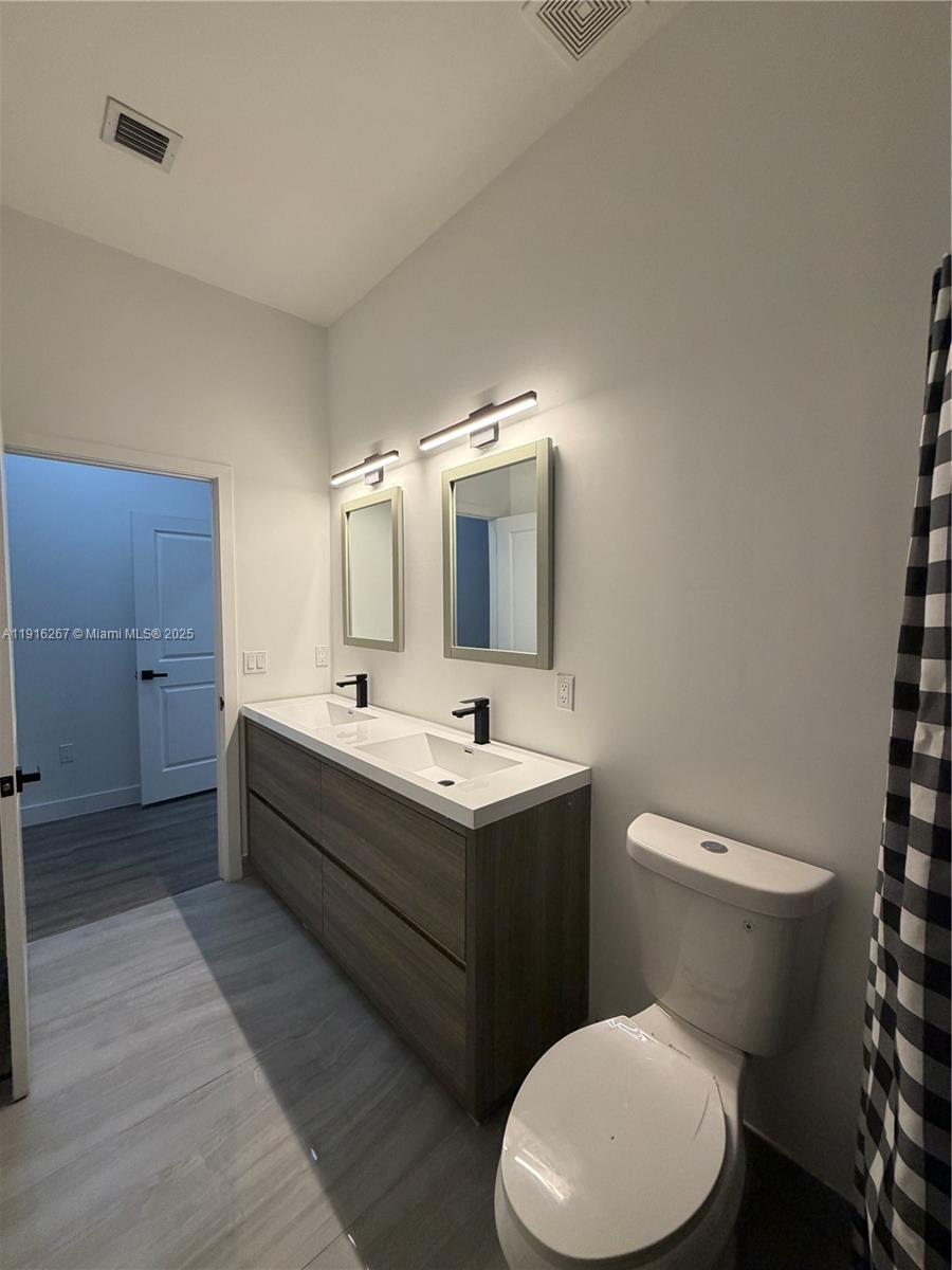 932 Southwest 10th Street, Unit 3 Hallandale Beach, FL 33009 - Photo 18 of 22 a bathroom with a toilet sink and mirror