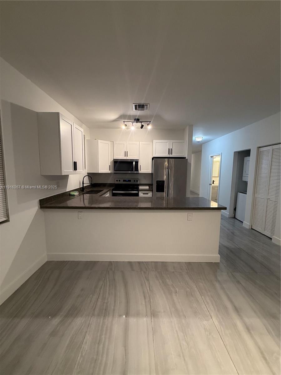 932 Southwest 10th Street, Unit 3 Hallandale Beach, FL 33009 - Photo 5 of 22 a large white kitchen with stainless steel appliances granite countertop a stove a sink and a refrigerator