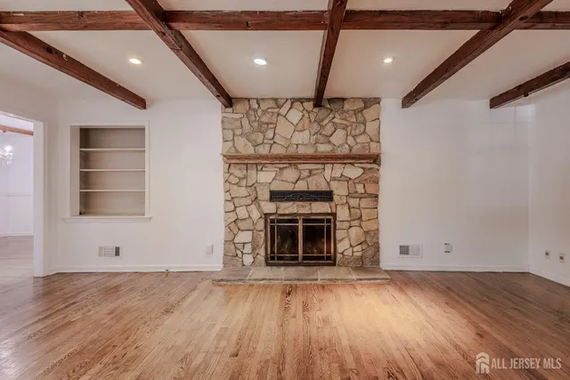 an empty room with wooden floor a fireplace and windows
