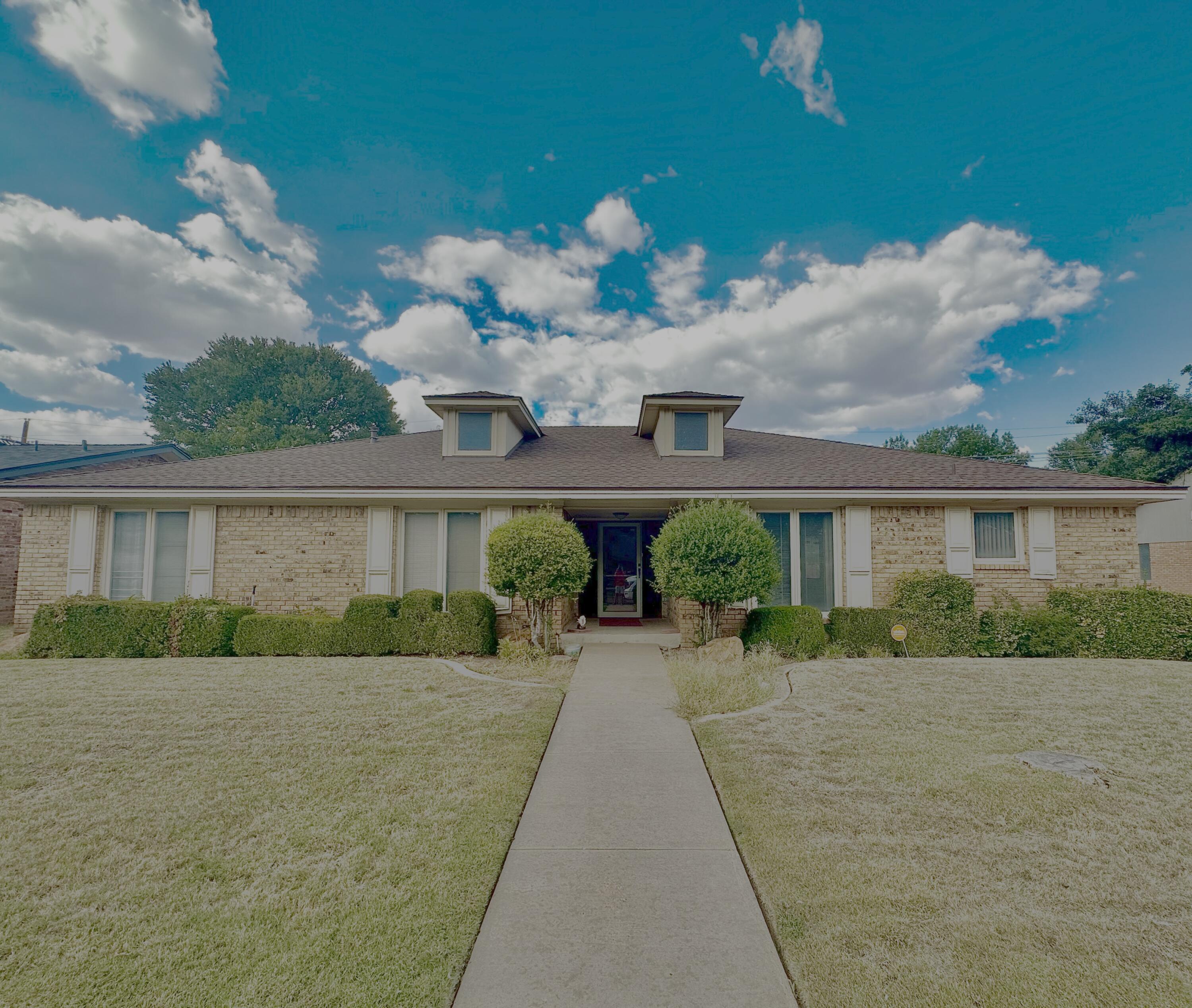 a front view of a house with a yard and potted plants