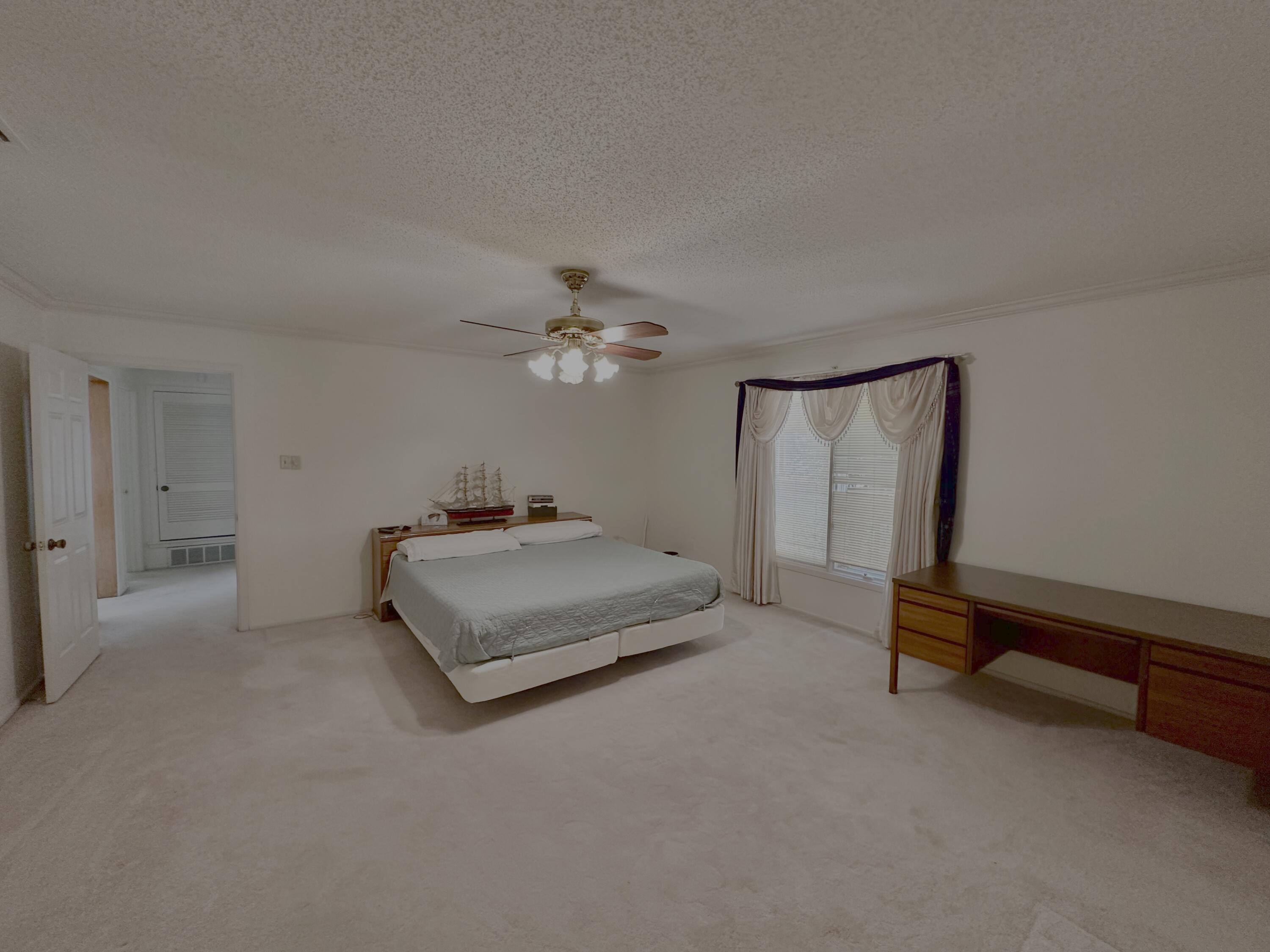 4610 88th Street Lubbock, TX 79424 - Photo 11 of 20 a spacious bedroom with a bed and a chandelier