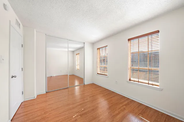 a view of an empty room with wooden floor and a window