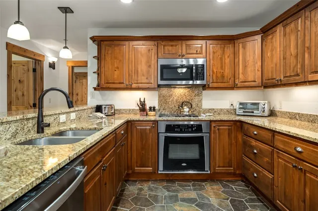 a kitchen with granite countertop a sink stove and microwave