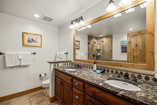a bathroom with a granite countertop double vanity sink and a mirror