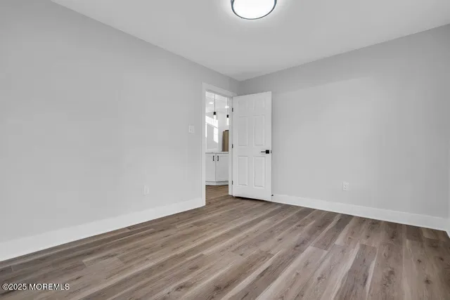 a view of an empty room with wooden floor and white wall