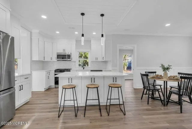 a kitchen with kitchen island granite countertop a table chairs stove microwave and cabinets