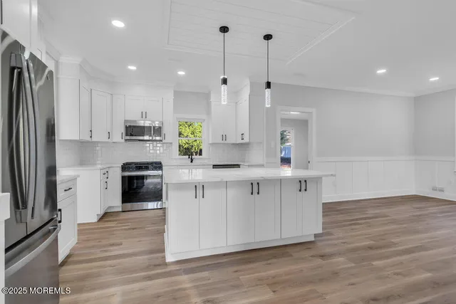 a kitchen with stainless steel appliances white cabinets a sink a stove a refrigerator and a counter top space