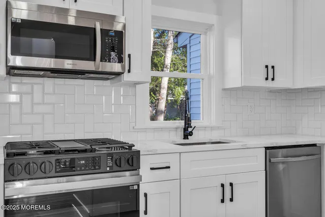 a kitchen with stainless steel appliances white cabinets and a stove top oven