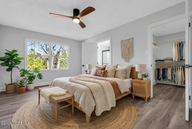 an empty room with wooden floor chandelier fan and windows
