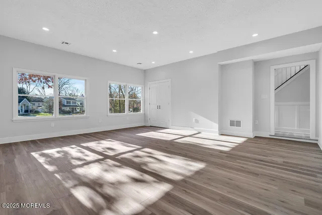 a view of an empty room with window and wooden floor