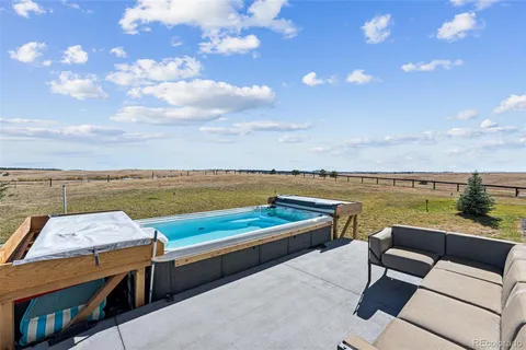 a view of a terrace with lawn chairs and ocean view