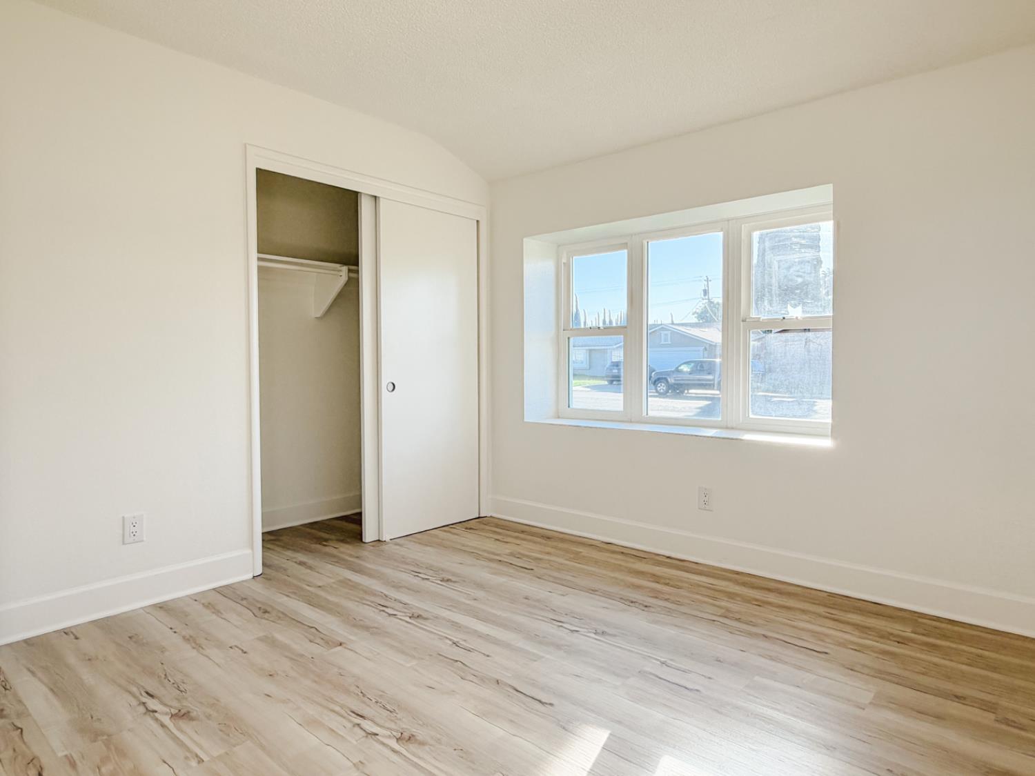 878 Carol Avenue Merced, CA 95341 - Photo 24 of 41 an empty room with wooden floor and windows