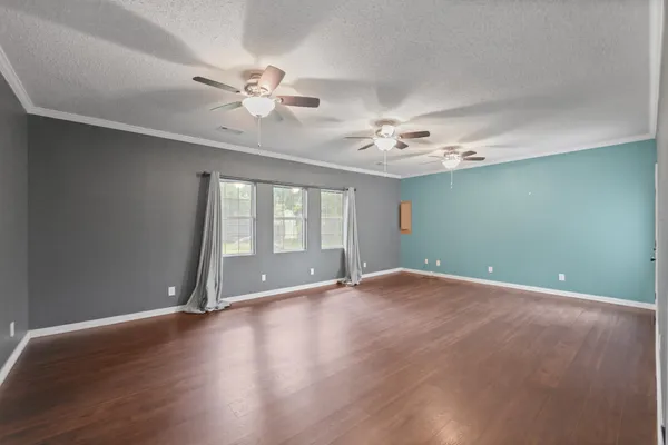 a view of an empty room with window and wooden floor