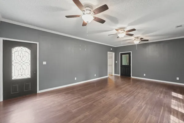 a view of an empty room with window and wooden floor