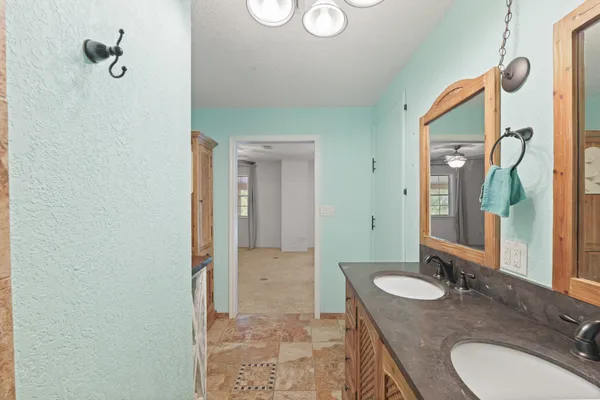 a bathroom with a granite countertop sink a mirror and a shower