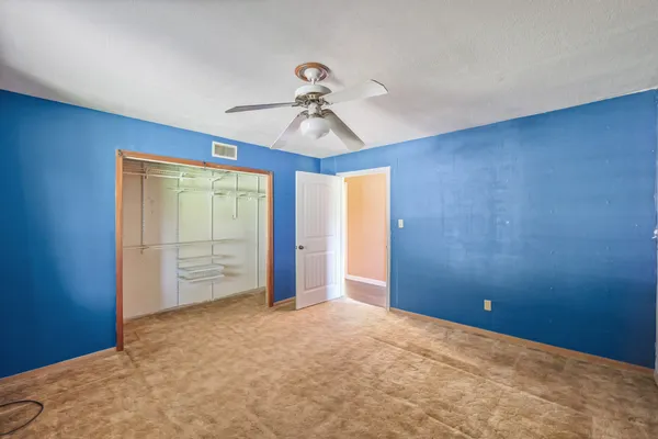 a view of an empty room and chandelier fan