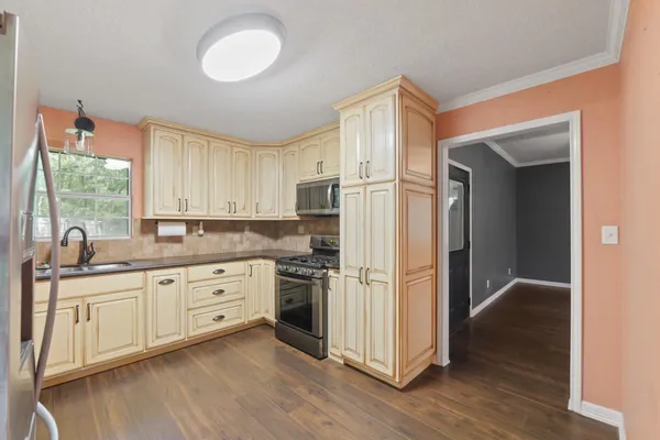 a kitchen with stainless steel appliances granite countertop a refrigerator a sink and white cabinets