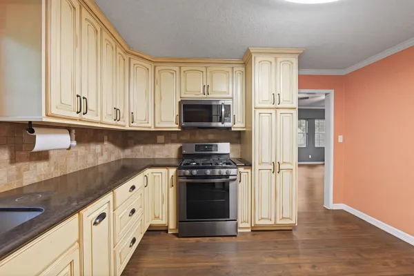 a kitchen with granite countertop a stove top oven microwave and refrigerator