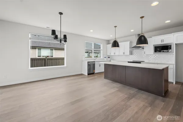 a large kitchen with stainless steel appliances kitchen island granite countertop a stove a sink and a wooden floor