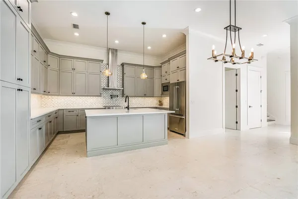 a large kitchen with a refrigerator a sink dishwasher a stove and white cabinets with wooden floor