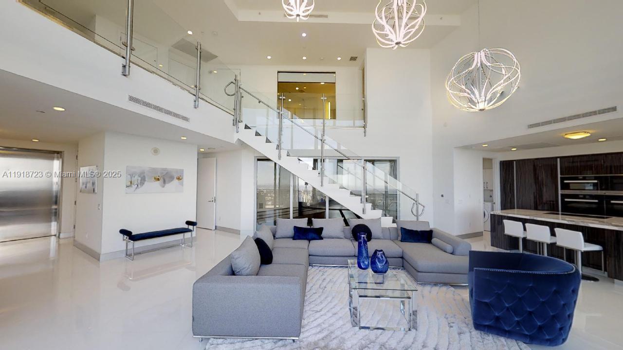 18555 Collins Avenue, Unit 4804 Sunny Isles Beach, FL 33160 - Photo 25 of 51 a living room with furniture and a chandelier