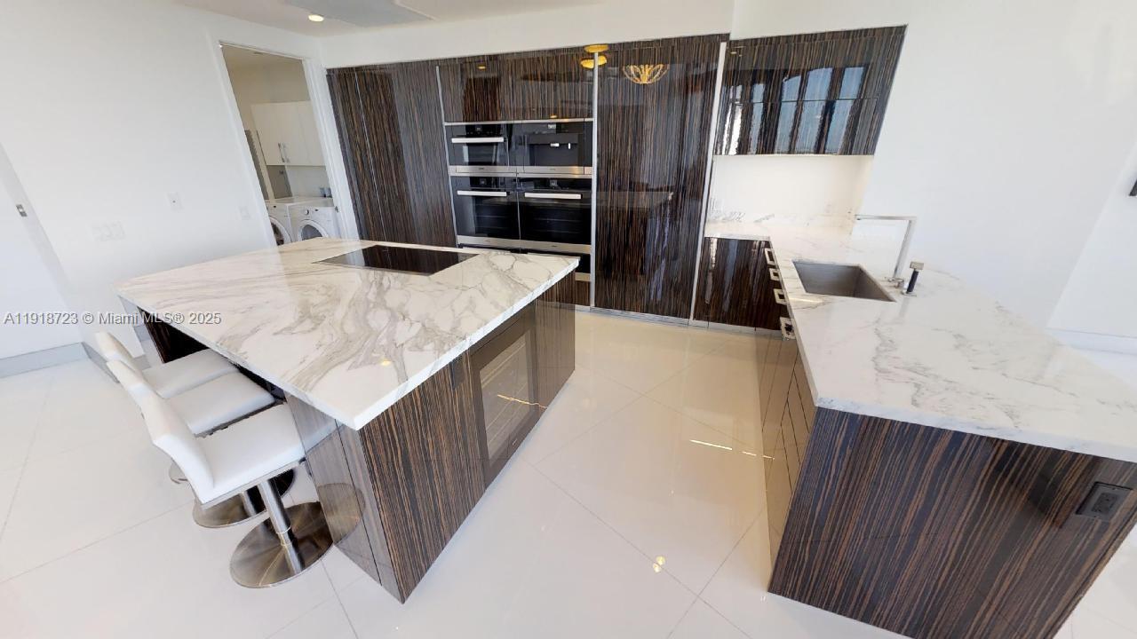 18555 Collins Avenue, Unit 4804 Sunny Isles Beach, FL 33160 - Photo 32 of 51 a kitchen with cabinets and chairs