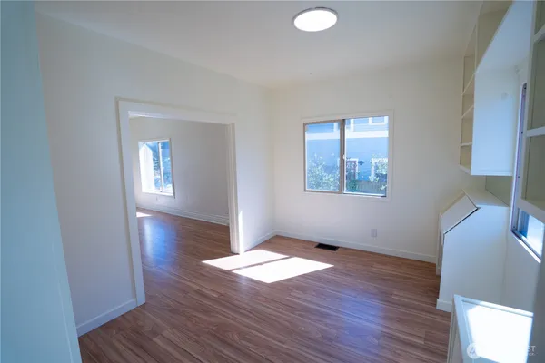 an empty room with wooden floor and windows