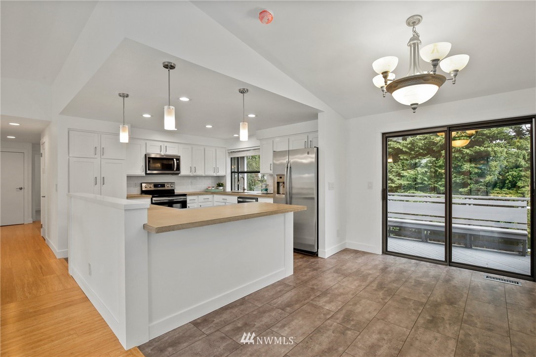 15504 Southeast 178th Place Renton, WA 98058 - Photo 5 of 40 a kitchen with stainless steel appliances kitchen island granite countertop a refrigerator oven a sink dishwasher and white cabinets with wooden floor