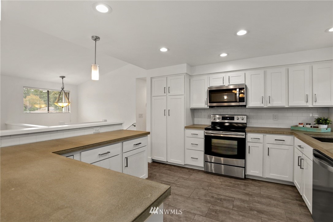 15504 Southeast 178th Place Renton, WA 98058 - Photo 9 of 40 a kitchen with stainless steel appliances granite countertop a sink a stove a microwave a center island and cabinets
