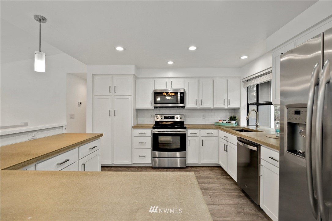 15504 Southeast 178th Place Renton, WA 98058 - Photo 10 of 40 a kitchen with stainless steel appliances granite countertop a refrigerator a stove and a sink with wooden floor