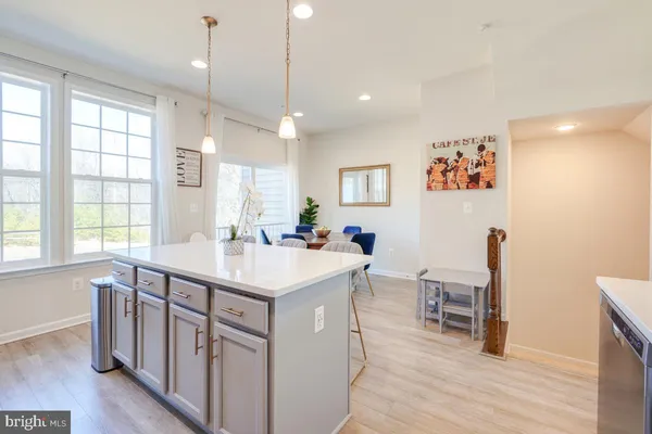 a kitchen with stainless steel appliances granite countertop a stove a sink a microwave a refrigerator and white cabinets with wooden floor