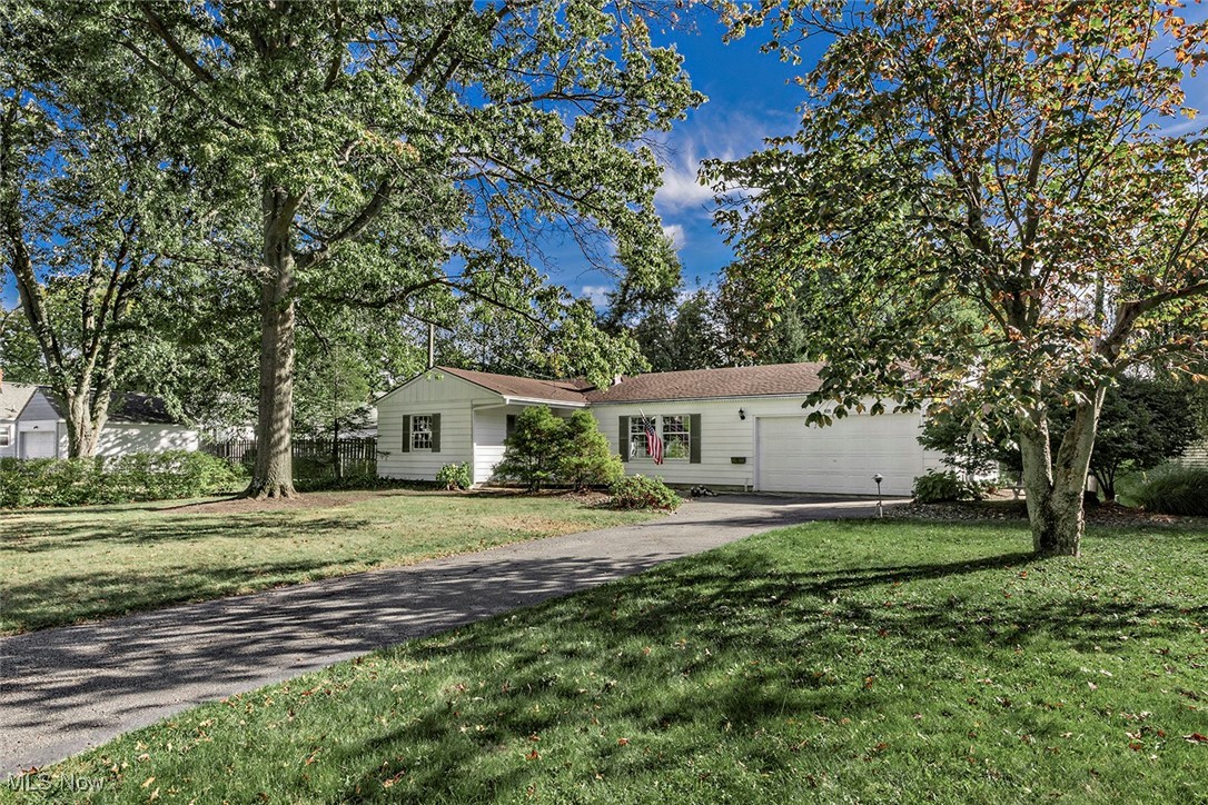 Ranch-style home featuring driveway, a front lawn, and a garage