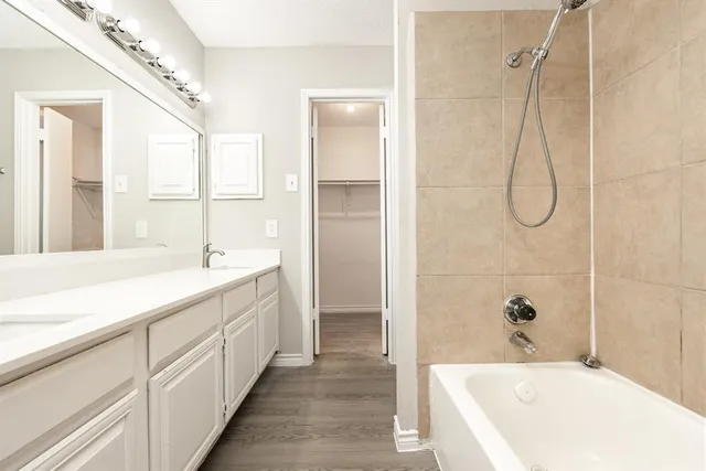 a spacious bathroom with a granite countertop sink a mirror and a bathtub
