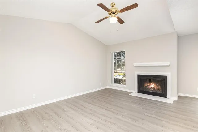 a view of a livingroom with a fireplace a ceiling fan and wooden floor