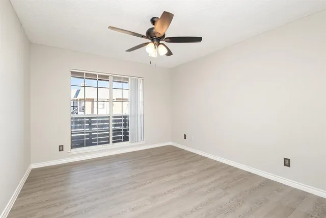 an empty room with wooden floor fan and windows