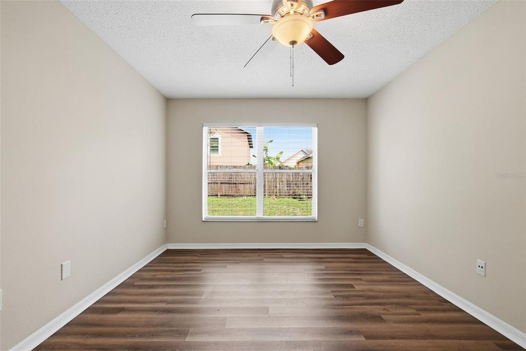 617 Greys Ferry Road Orlando, FL 32811 - Photo 16 of 35 an empty room with wooden floor chandelier fan and windows