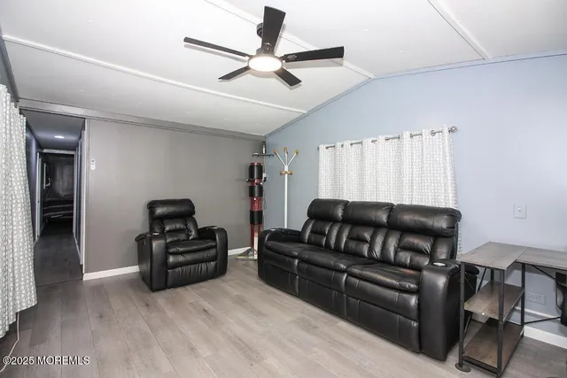 a living room with stainless steel appliances furniture dining table and wooden floor