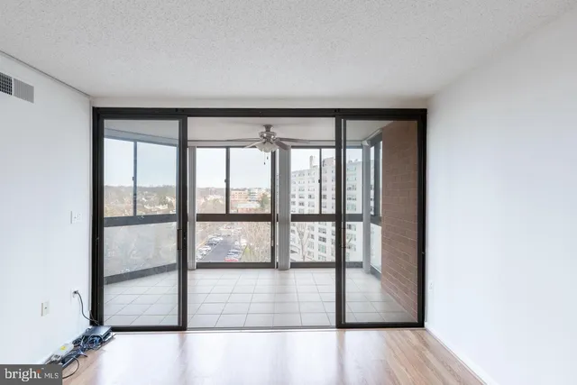 a view of empty room with wooden floor and fan