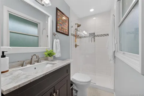 a bathroom with a granite countertop sink a toilet and a mirror