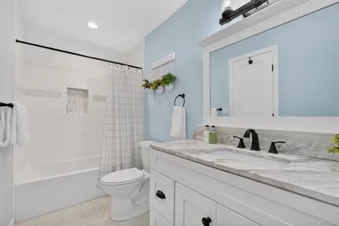 a bathroom with a granite countertop sink a toilet and shower