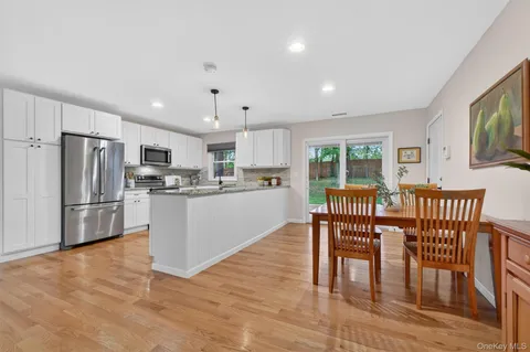 a kitchen with stainless steel appliances granite countertop a refrigerator a stove a dining table and chairs with wooden floor